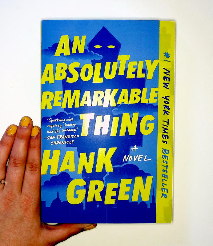 a green and dark blue cover with a looming geographic figure with bright colored eyes in the distance