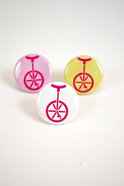 a one inch button with an illustration of a unicycle