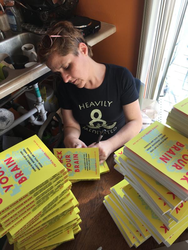 Dr. Faith signing huge stacks of Unfuck Your Brain, the non-digital version