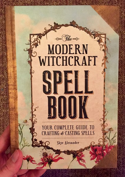 Cover of The Modern Witchcraft Spell Book: Your Complete Guide to Crafting and Casting Spells which features a border of greenery and flowers around the title