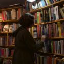A woman browses full bookshelves
