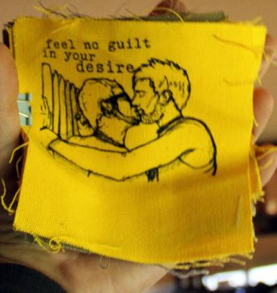 patch with image of two men kissing and the text "feel no guilt in your desire"