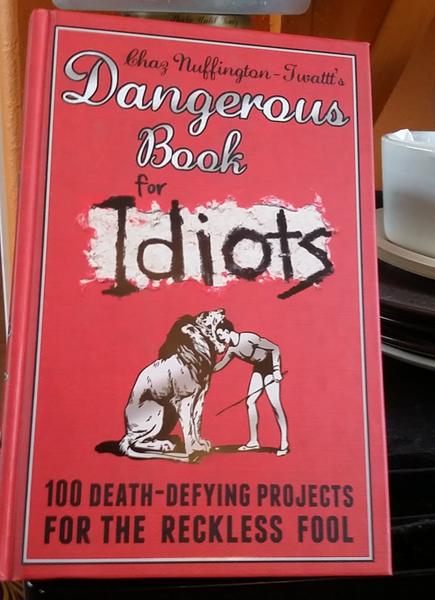 Dangerous Book for Idiots by Chaz Nuffington-Twatt [a circus man puts his head inside a lion's]