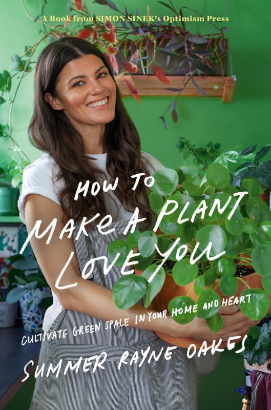 a smiling white woman in overalls hugs a potted plant