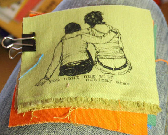 patch with image of two people with arms around each other and the text: "you can't hug with nuclear arms"