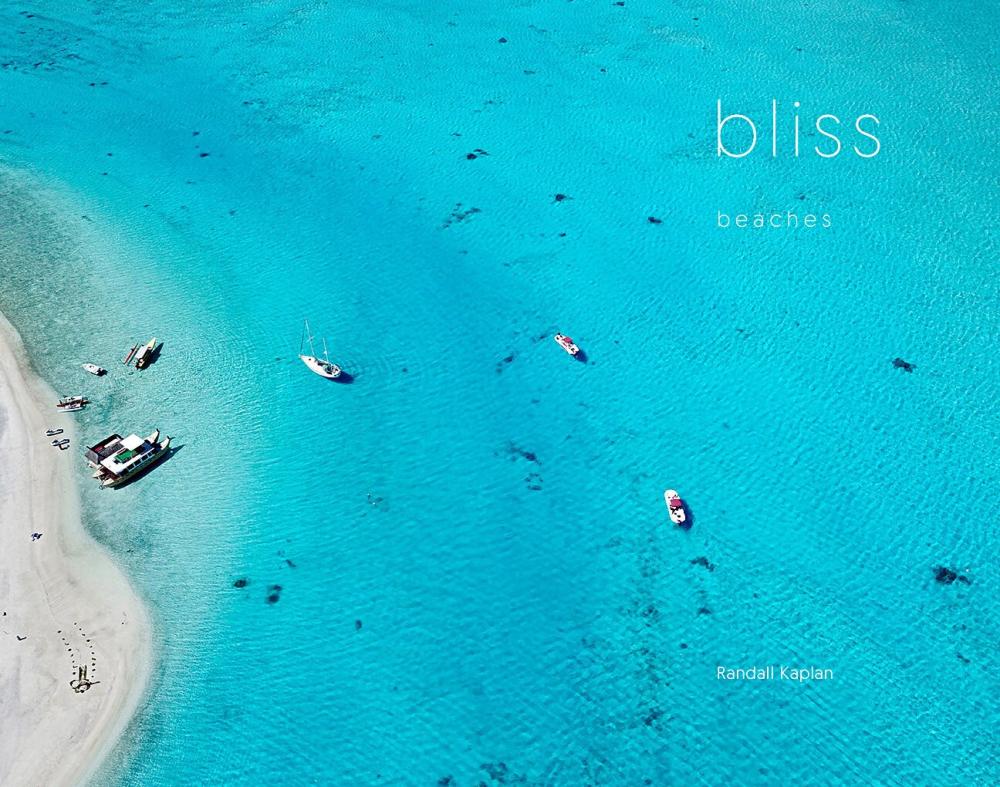 Aerial shot of a blue ocean and the shore with small boats 