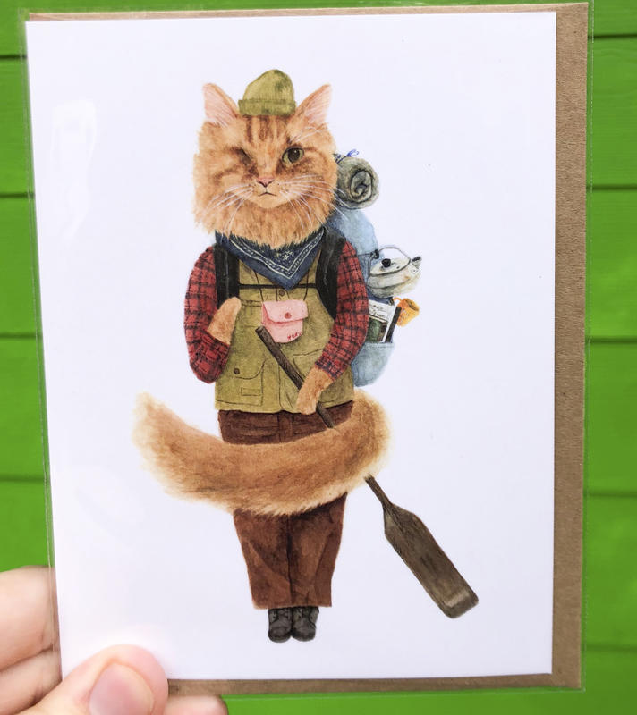 A cat dressed in the trappings of an explorer, complete with a stuffed backpack and a paddle in hand.
