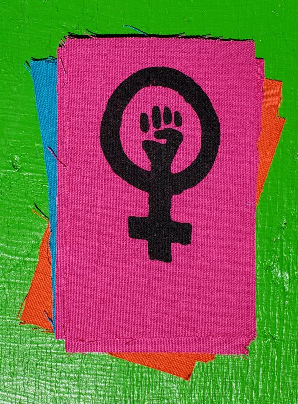 Canvas patch showing a raised fist inside a woman symbol