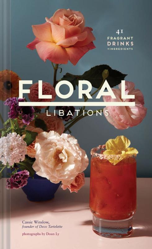 vase with flowers next to a red drink with a flower in it