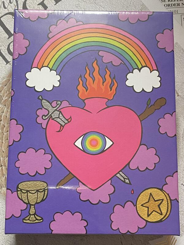 illustration of  all-seeing eye inside sacred heart under a rainbow, surrounded by tarot suit symbols. 