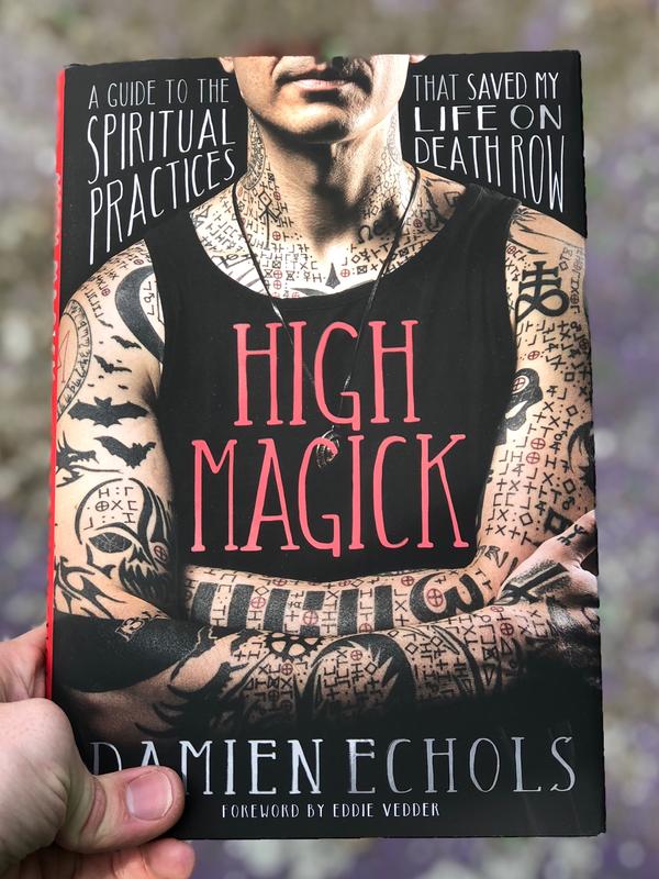book with tattooed man on the cover with a black tank top that says high magick and writing around the man