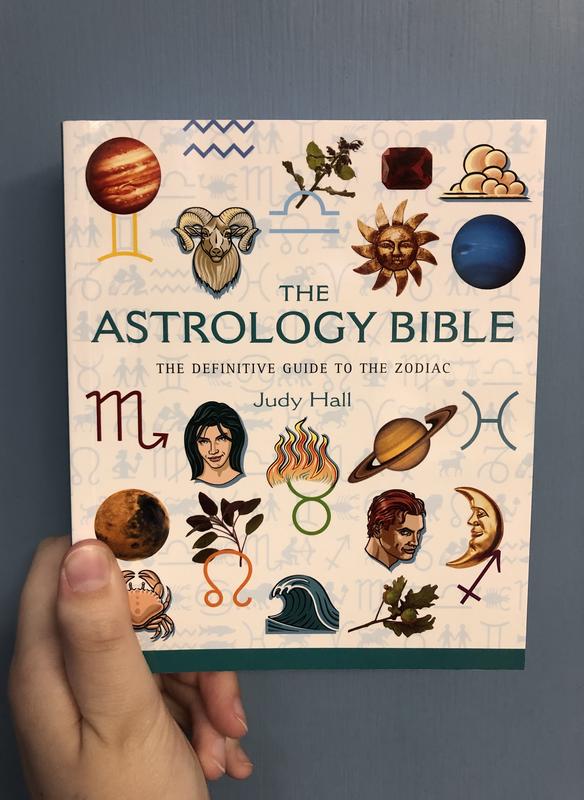 Various astrological signs scattered across the cover. The moon, planets, zodiac signs. 