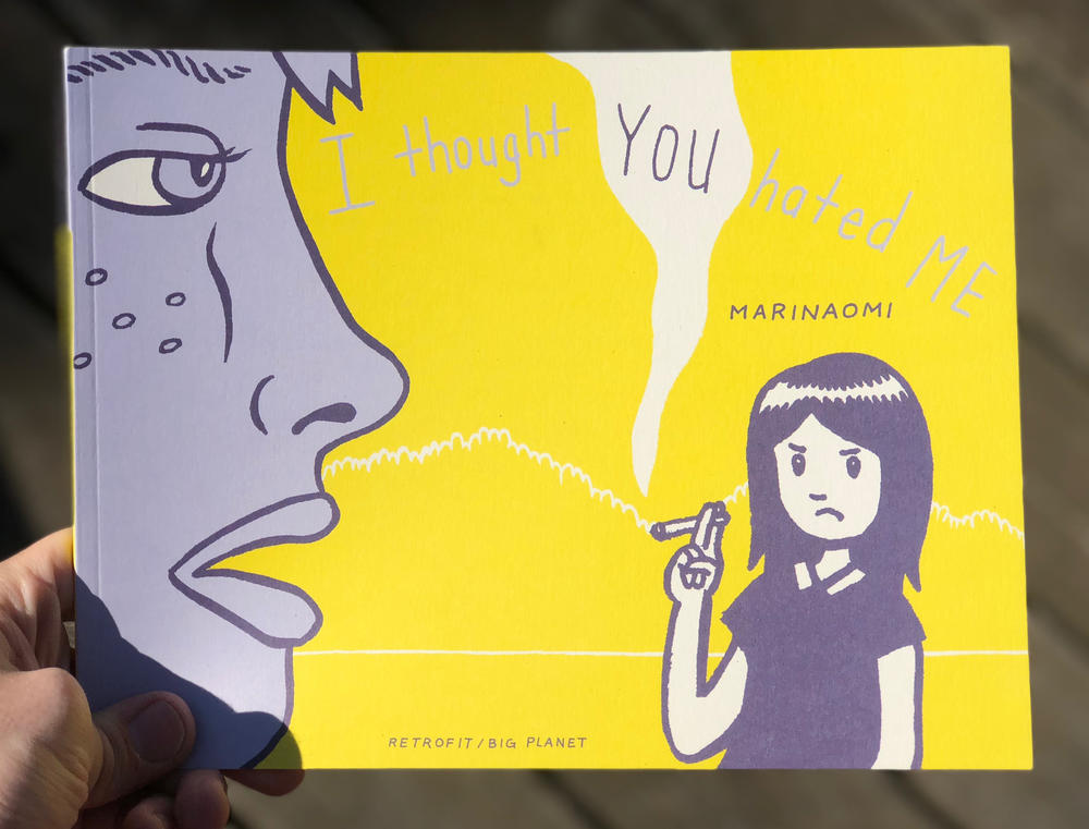 A woman holding a cigarette frowns at a person talking to her.