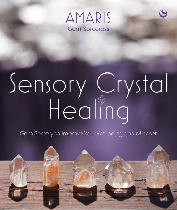 five quartz crystals lined up on a wooden background with a blurred two tone white-blue background