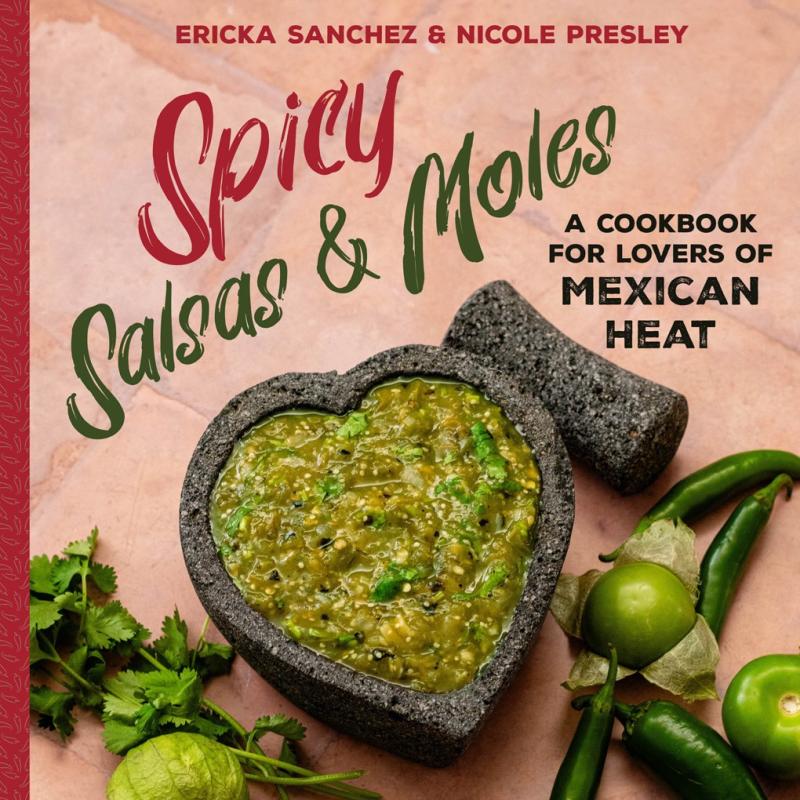 Black stone mortar in the shape of a heart with green salsa on a counter with different foods