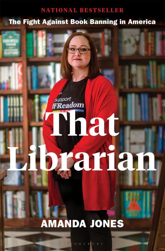 librarian in a red cardigan stands in front of a full bookshelf