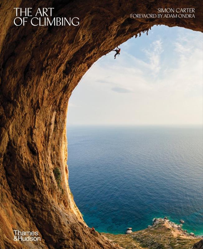 Wide shot of a climber on a curved rock wall overlooking the large body of water