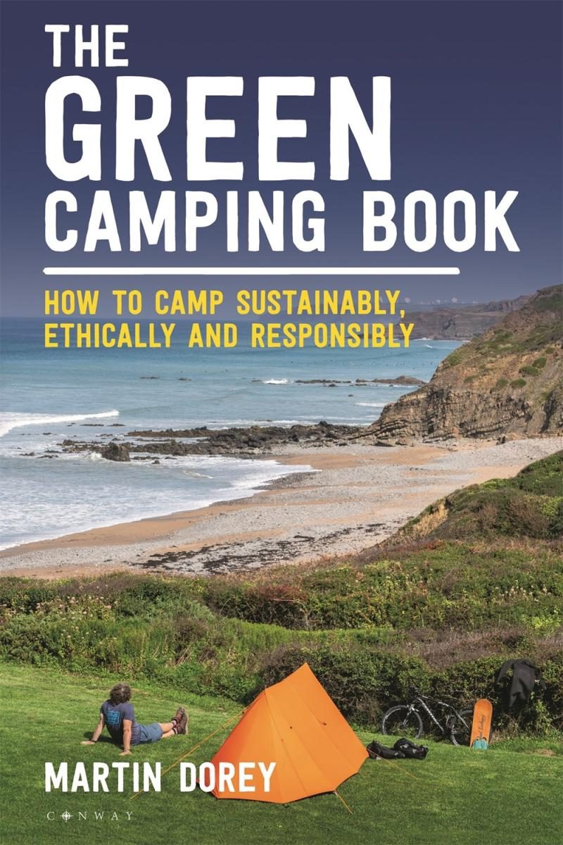 person camped out in an orange tent next to the coast