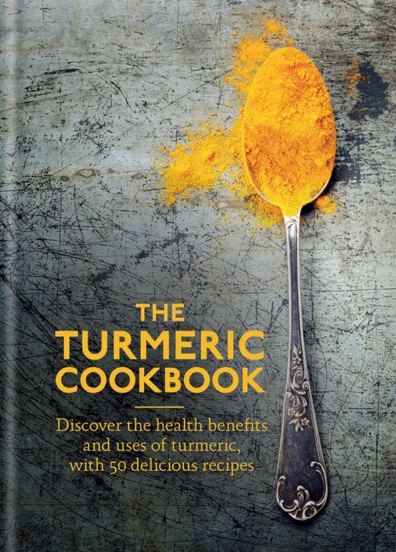off-center spoon full of turmeric spilling from the sides over a worn background