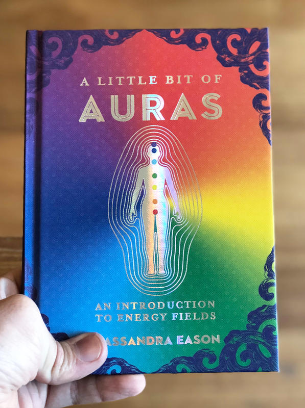 Cover of A Little Bit of Auras, which features the outline of a human with the 7 chakra points added in color with lines surrounding the figure as if to imply an aura