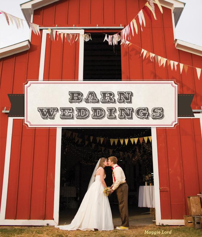 A couple kiss in front of a barn.