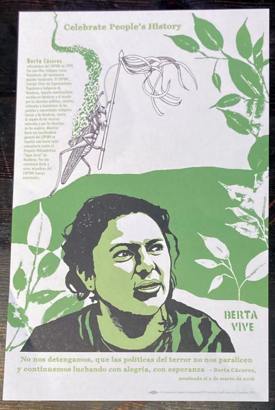 an illustration of Berta Cáceres in front of a green banner and some plants, along with a cricket holding a banner