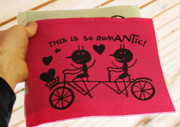 patch with image of two ants on a tandem bike with hearts around them and the text "this is so romantic!"