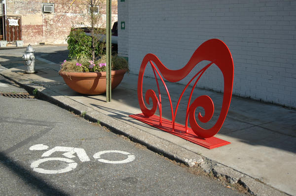 a photo of an artistic bicycle rack next to a bike lane