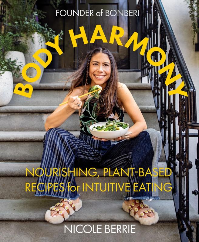 A happy, smiley lady sits on some stairs eating bokchoy.