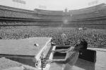 black and white photograph of elton john playing on stage in front of large crowd