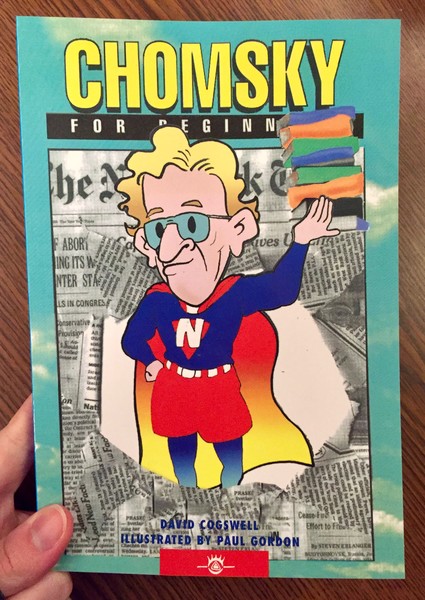 Book cover depicting Chomsky in a superhero costume, holding up some books in front of a newspaper background