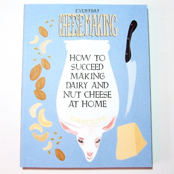 A blue book cover with illustrations of a goat, jar, nuts, a knife, and cheese