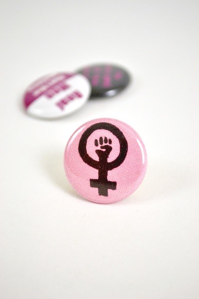 pink button showing a feminist symbol with a fist in it