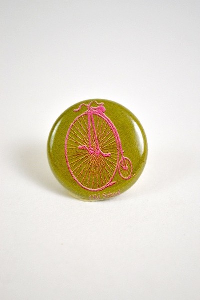a button with a picture of a pennyfarthing bicycle and the words old school