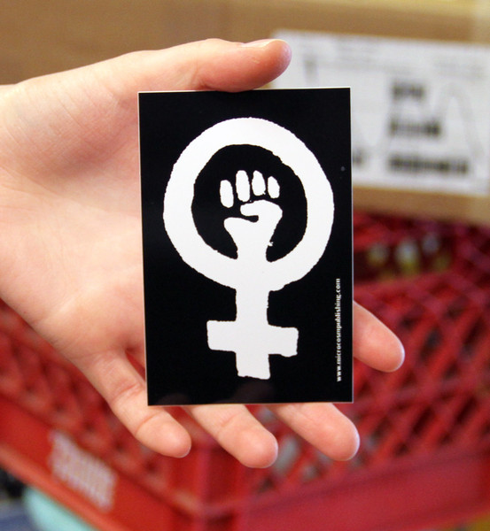 A black vinyl sticker showing a white woman symbol with a fist in the middle