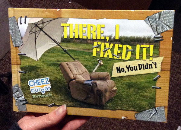 Cover of There I Fixed It!: (No, You Didn't) [A brown chair with a cupholder and umbrella attached sits in a green field.]