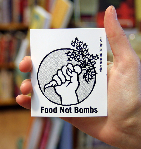a hand holding a carrot with the words FOOD NOT BOMBS