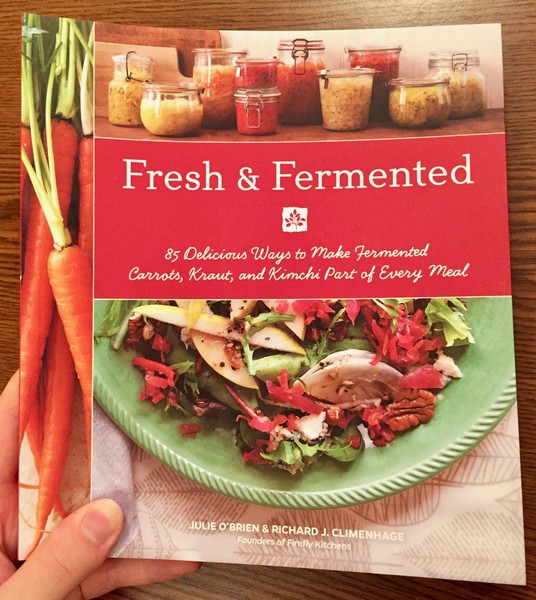 a book cover depicting a plate of salad next to some fresh carrots lying under some glass bottles.