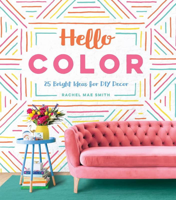 pink couch on teal carpet with rainbow line cover with orange pink and green text