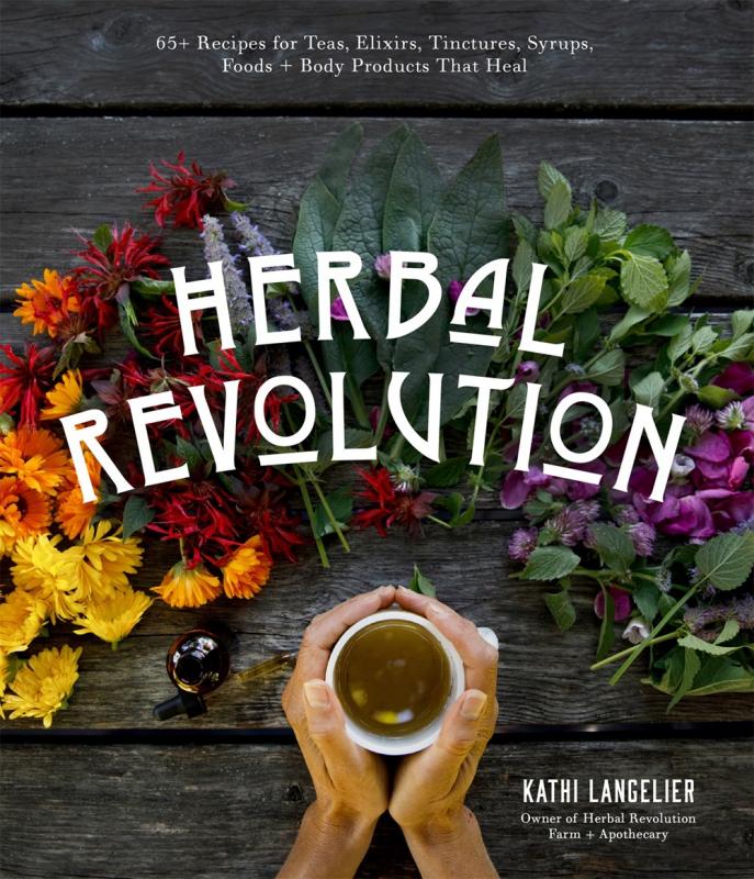 two hands holding a cup of tea, surrounded by an assortment of flowers and herbs.