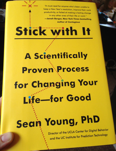 Hand holding copy of Stick With It