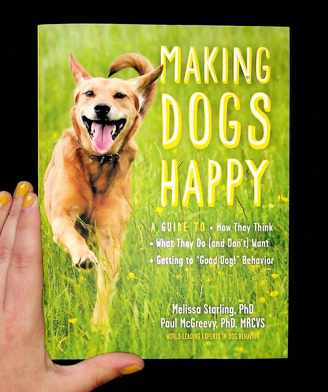 a happy dog running through grass next to the book's title, "Making Dogs Happy" in a yellow print