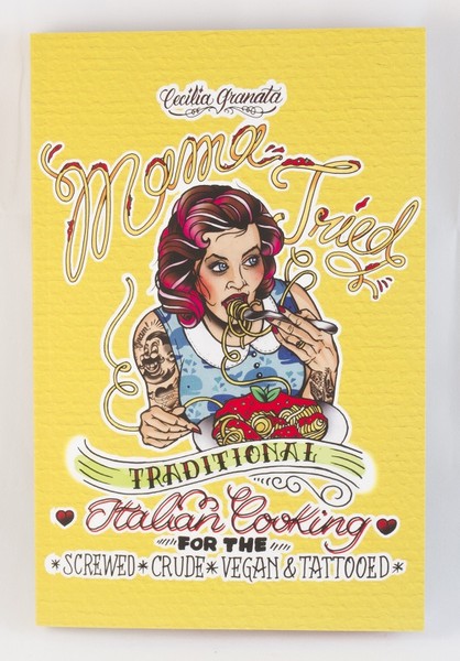A tattooed woman eating some good-looking spaghetti and "meat"balls on the yellow cover of a book