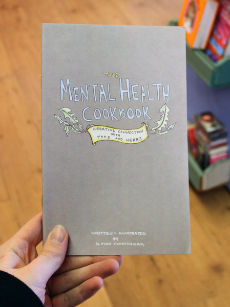 Cover of Mental Health Cookbook: Creating Connections with Food and Herbs which has a couple of drawings of leaves surrounding the title on the otherwise plain cover 