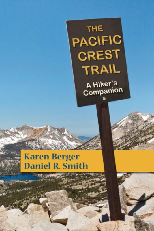 a trail sign, with mountains in the distance