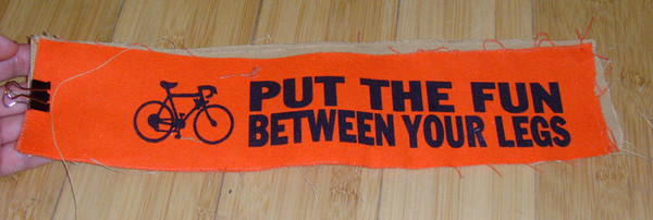 long patch with bicycle logo and text "put the fun between your legs"