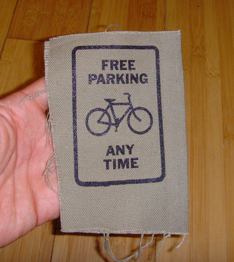 a canvas patch that says free parking any time with a drawing of a bicycle
