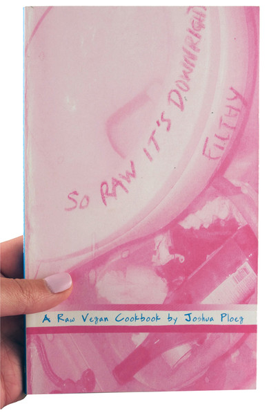 A pink book with a photo of a toilet (title written on the seat) and a plastic container next to it containing a wine bottle