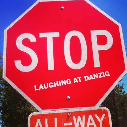 A stop sign with a "laughing at danzig" sticker on it