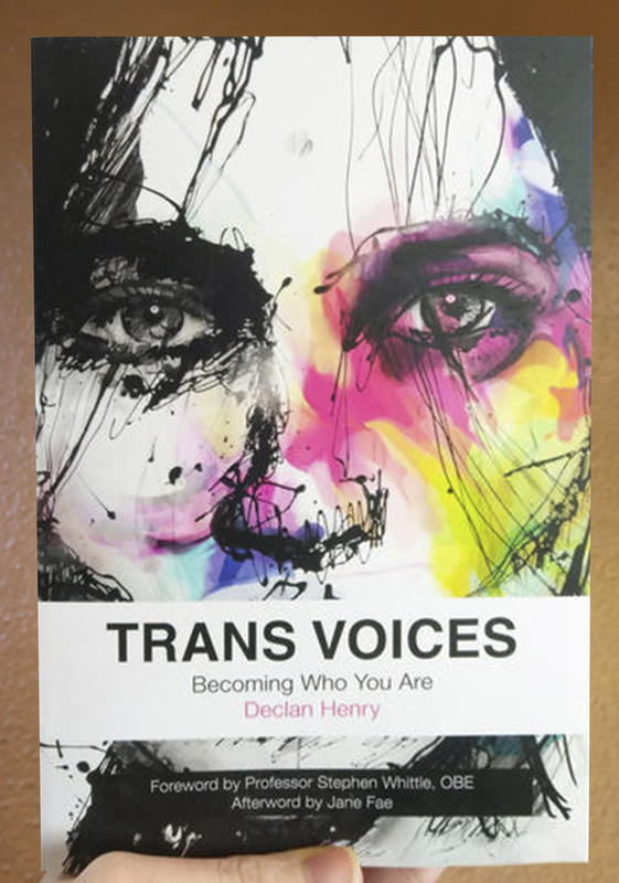 A face in black and white splashed with a myriad of color made to look like a black eye. The white text box with the title - Trans Voices - covers the face's mouth.